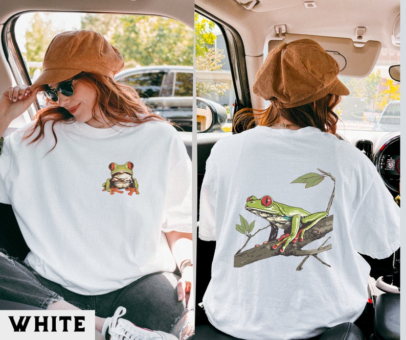 May include: White t-shirt with a green tree frog graphic on the front and a green tree frog on a branch graphic on the back.