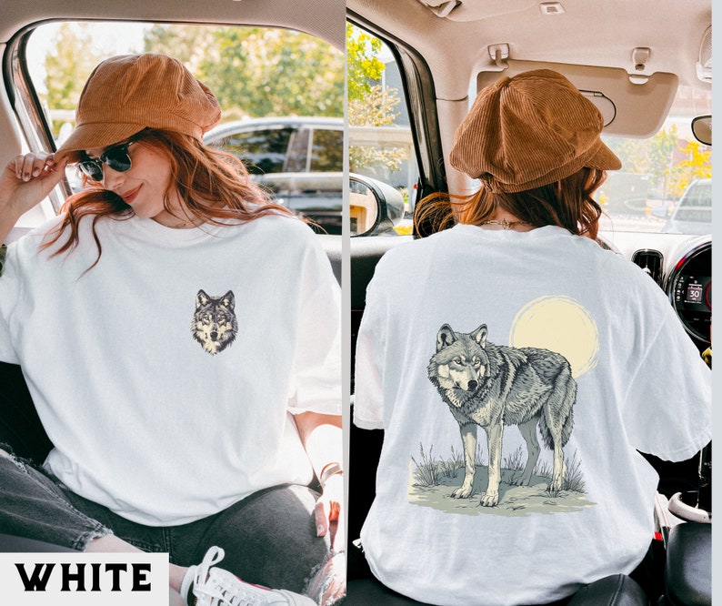 May include: Two white t-shirts with wolf graphic designs. One shirt features a wolf's head, the other a wolf howling at the moon.