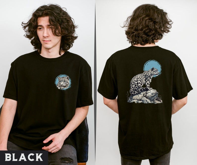 May include: Black t-shirt featuring a graphic of a snow leopard on a rock with a blue circle behind it. The graphic is on the back of the shirt. The shirt is being modelled by a person.