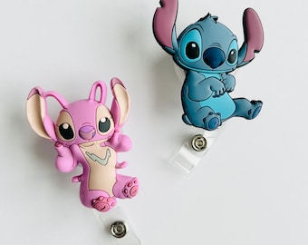 May include: Two Stitch character badge holders. One is blue and the other is pink. Both are holding their arms up in the air.