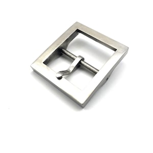Peut inclure: Une boucle de ceinture en métal argenté avec un cadre carré et un fermoir coulissant.