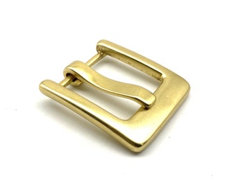May include: A gold-toned metal buckle with a rectangular shape and a smooth, polished finish. The buckle has a single prong and a curved, spring-loaded bar.