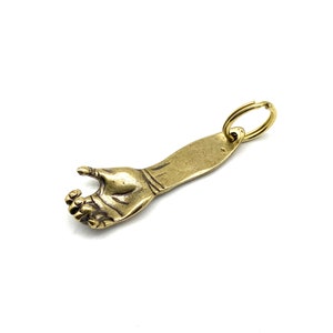 May include: A brass bottle opener shaped like a hand with a ring attached to the wrist.
