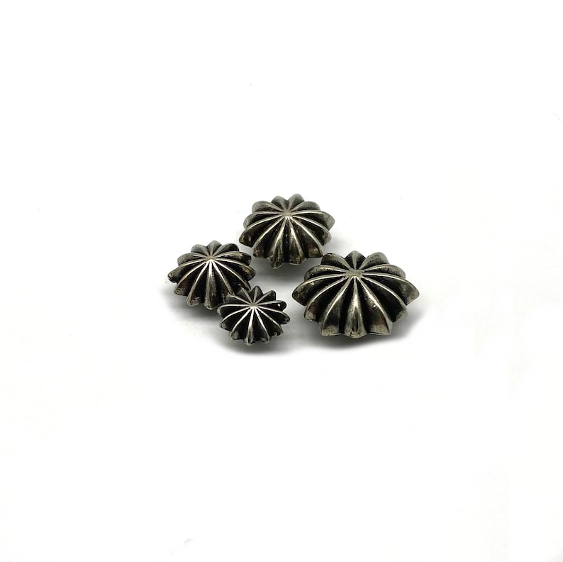 May include: Four silver-toned metal star-shaped buttons with a raised, textured design. The buttons are different sizes.