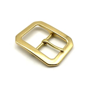 May include: A gold-toned metal buckle with a rectangular shape and a smooth finish.