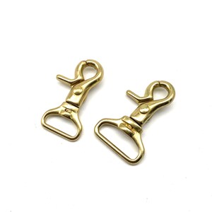 May include: Two gold-toned metal swivel snap hooks. The hooks have a rectangular loop and a spring-loaded gate.