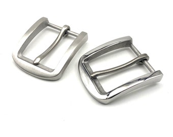 May include: Two silver metal belt buckles. Both buckles are rectangular with rounded edges. The buckles are made of a smooth metal and have a polished finish.