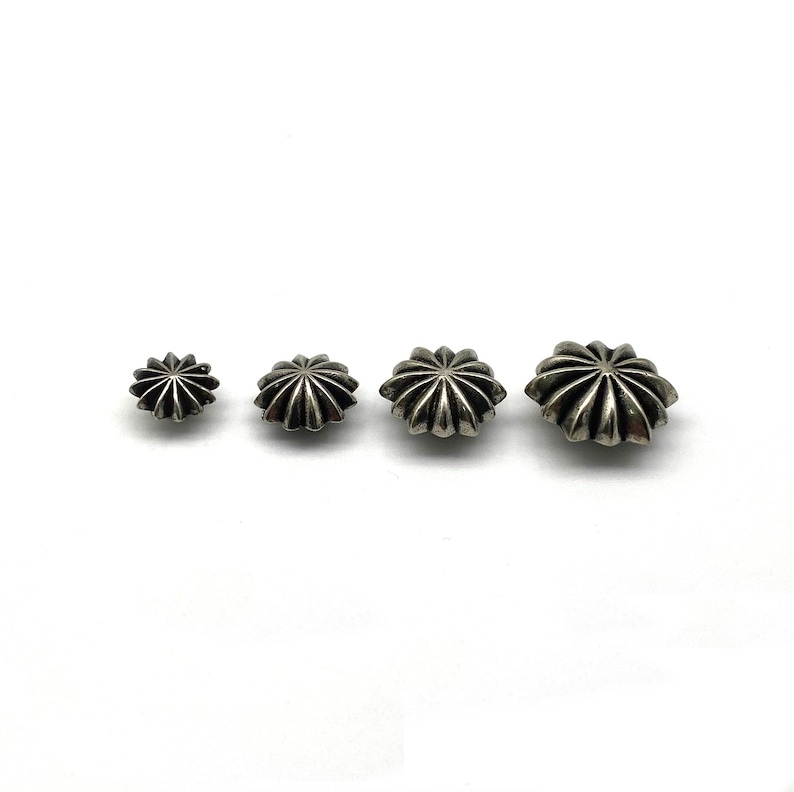 May include: Three silver star-shaped studs of different sizes. The studs have a raised, textured design.