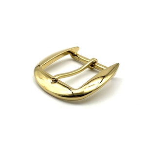 May include: A gold-toned metal belt buckle with a smooth, rounded design.