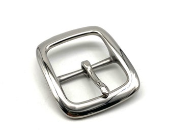 May include: A silver metal buckle with a smooth, rounded finish. The buckle has a rectangular shape with rounded corners and a single, centered prong.