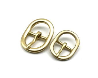 May include: Two oval-shaped brass buckles, one larger than the other. Both buckles have a smooth, polished finish.