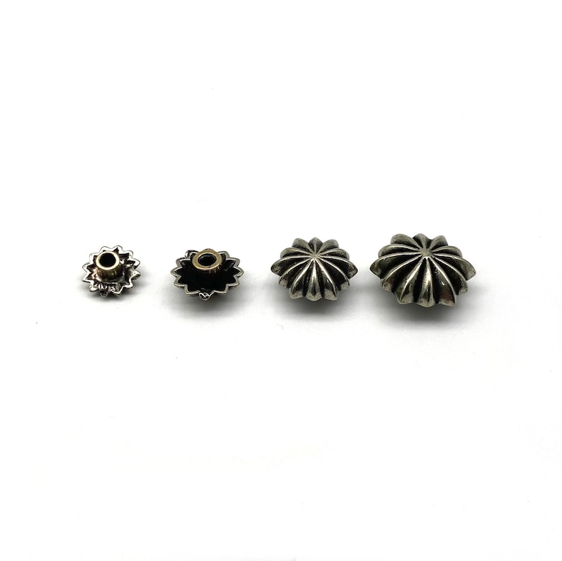 May include: Three silver star-shaped metal studs of different sizes. The studs have a raised, textured design and a small hole in the center.