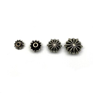 May include: Four silver star-shaped metal studs of varying sizes. The smallest stud has a gold center.