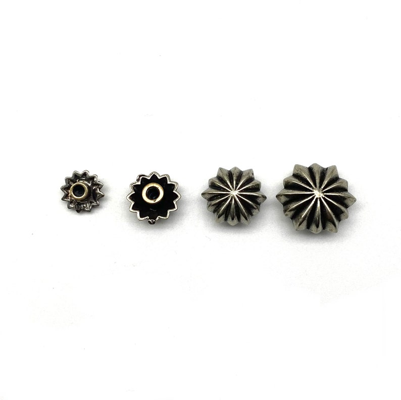 May include: Four silver star-shaped metal studs of varying sizes. The smallest stud has a gold center.