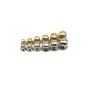 May include: Assortment of round, metal knobs in various sizes. The knobs are in two finishes: gold and silver.