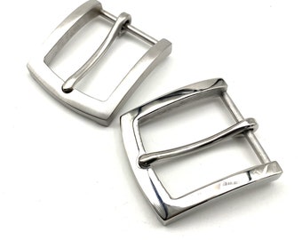 May include: Two silver metal belt buckles. The buckles are rectangular with rounded corners and have a smooth, polished finish.