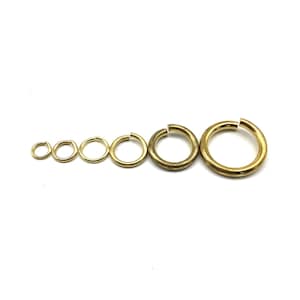 May include: A set of seven gold jump rings of varying sizes. The rings are arranged in order of size, with the smallest ring on the left and the largest ring on the right.
