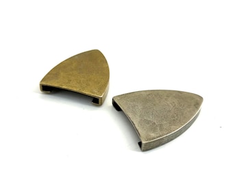 May include: Two metal decorative pieces in a triangular shape. One is a brass color, and the other is a silver color. Both have a curved edge and a slot on the bottom. The pieces are on a white background.