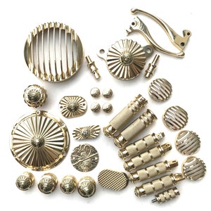 以下が含まれることがあります： ヘッドライトグリル、フットペグ、ハンドルコントロール、装飾的なアクセントなど、金メッキされたオートバイのパーツのセット。パーツには、ライオンの頭のデザインとサンバーストパターンが施されています。