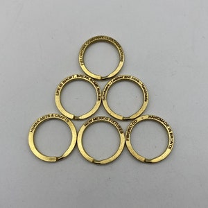 May include: Six gold key rings with different engraved sayings. The sayings include "Fieldwork Company - Leather House", "Life is Short. Break Some Rules", "Hukka Arts & Crafts", "New Mexico Fixtures", "Fiborio Co", and "Handmade in Bronte".