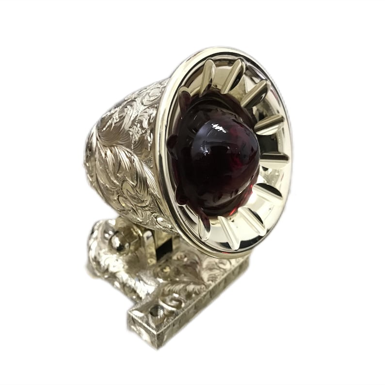 May include: A silver-plated, ornate, decorative automotive tail light with a red glass lens. The light has a detailed, engraved design and a base that is designed to be mounted on a vehicle.