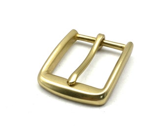 May include: A gold-toned metal belt buckle with a smooth, polished finish. The buckle has a rectangular shape with rounded corners and a single, curved prong.