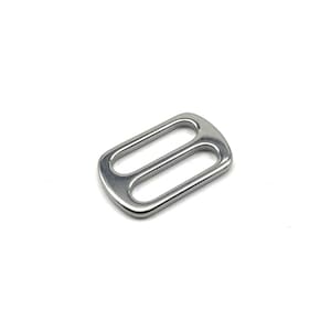 Peut inclure: Une boucle coulissante en métal argenté avec deux ouvertures. La boucle est conçue pour attacher des sangles ou des sangles.