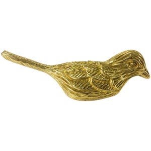 May include: A gold-colored metal bird figurine with detailed feather markings. The bird is perched with its head turned to the side.