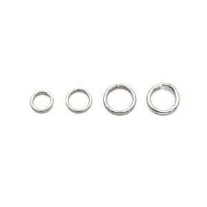 May include: Four silver-colored jump rings of varying sizes are arranged on a white background. The rings are circular, with a small gap in one side of the larger rings. These jewelry findings are used for connecting components in jewelry making.
