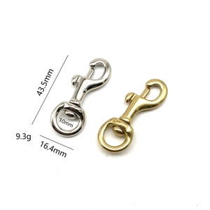 May include: Two metal clasps, one silver and one gold, with a 10mm diameter ring and a 16.4mm length. The clasps are 43.5mm tall and weigh 9.3g.
