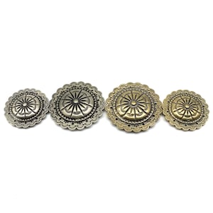 Puede incluir: Tres botones redondos de metal con un diseño floral decorativo. Los botones son de diferentes tamaños y tienen un acabado plateado y dorado.