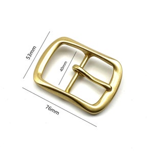 May include: A gold-toned metal belt buckle with rounded edges. The buckle measures 3 inches wide by 1.5 inches tall.
