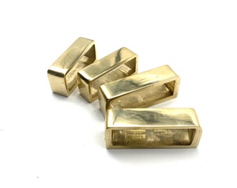 May include: Four gold-coloured metal rectangular buckles with rounded edges. The buckles are arranged in a staggered pattern.