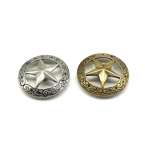 May include: Two metal star-shaped conchos. One is silver-coloured with a decorative border, and the other is gold-coloured with a similar border. Both are circular and feature a five-pointed star in the centre, suitable for Western-themed crafts.