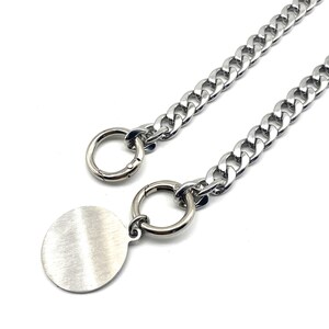 May include: A silver chain necklace with a round, brushed silver pendant and two silver rings. The chain is a curb chain style.