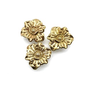 May include: Three gold-colored metal flower-shaped buttons. Each button has a raised, detailed design.