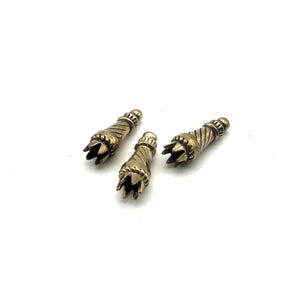 May include: Three antique brass-colored metal decorative objects. Each has a textured, spiraled body and a claw-like, multi-pronged end. The objects are arranged on a white background.