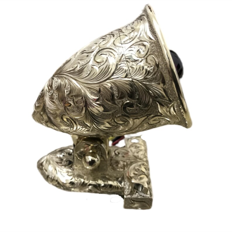May include: A gold-plated, engraved, decorative spotlight with a red lens. The spotlight has a floral design and is mounted on a bracket.