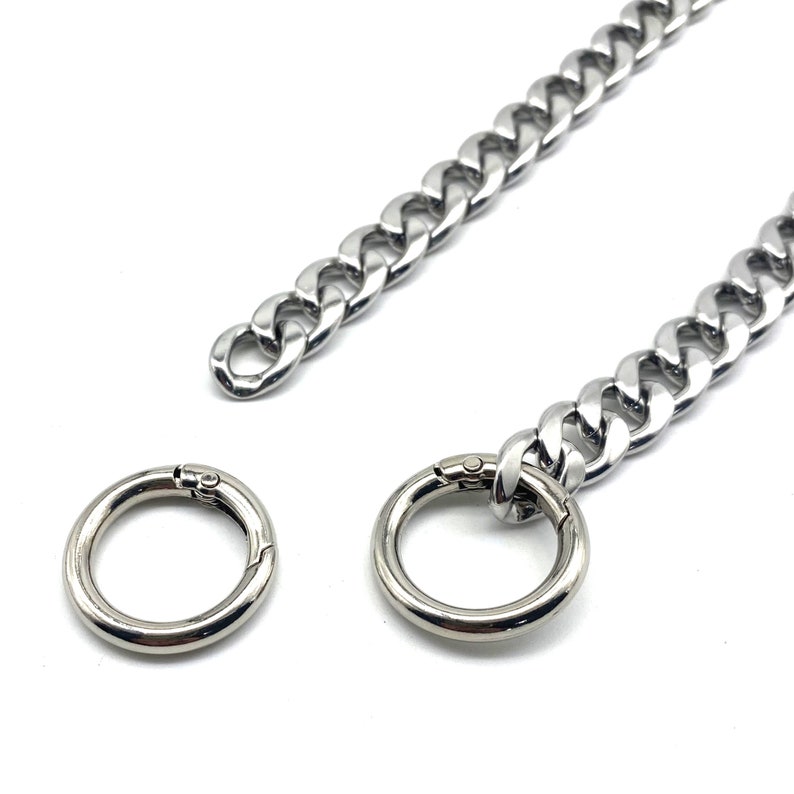 May include: A silver chain with two silver clasps. The chain is made of thick, flat links.