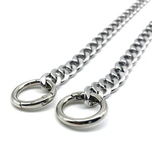 May include: A silver chain with two silver clasps. The chain is thick and has a curb link design.