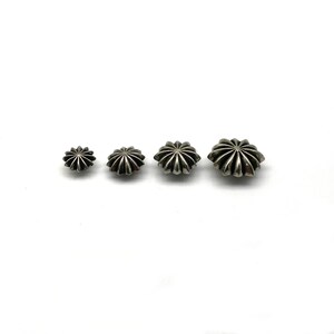 May include: Four silver star-shaped studs of varying sizes. The studs have a raised, textured design.