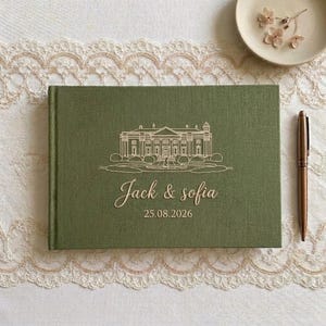 Puede incluir: Un libro de visitas rectangular cubierto de tela verde oliva con un dibujo lineal dorado de una gran finca, los nombres Jack & Sofia y la fecha 25.08.2026 grabados en la portada, acompañado de un bolígrafo dorado.