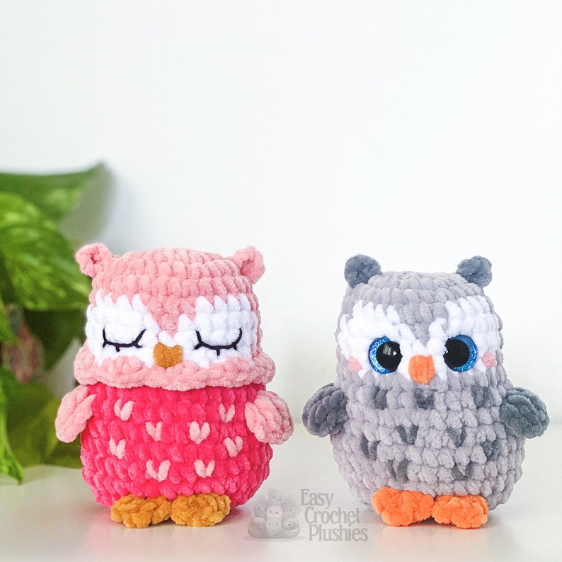 Puede incluir: Dos peluches de b&uacute;ho de crochet, uno rosa con los ojos cerrados y un patr&oacute;n de coraz&oacute;n, el otro gris con ojos azules y un patr&oacute;n texturizado. Easy Crochet Plushies.