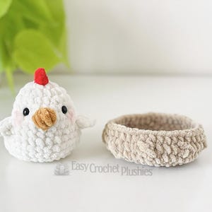 May include: A white crochet chick with a red comb and a tan beak sits beside a small, tan crochet basket. The chick has black eyes and pink cheeks. The items are handmade and suitable for Easter.