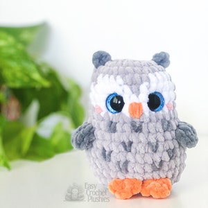 Puede incluir: Un juguete de peluche de b&uacute;ho gris tejido a crochet con ojos azules y un pico naranja. El b&uacute;ho tiene pelaje blanco alrededor de los ojos y patas naranjas.