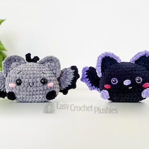 Puede incluir: Dos murci&eacute;lagos de peluche tejidos a crochet, uno gris con alas moradas y otro negro con alas moradas. Ambos murci&eacute;lagos tienen ojos negros y mejillas rosadas.