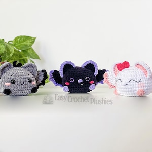 Puede incluir: Tres murci&eacute;lagos de peluche tejidos a crochet en diferentes colores. El murci&eacute;lago de la izquierda es gris con ojos negros y una nariz rosa. El murci&eacute;lago del medio es negro con alas moradas y mejillas rosadas. El murci&eacute;lago de la derecha es blanco con alas rosadas y un lazo rosa. Easy Crochet Plushies.