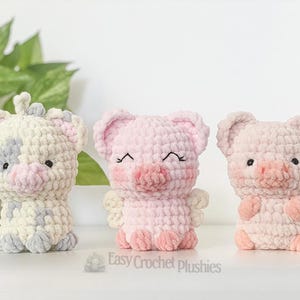 May include: Three handmade crochet plushies: a cow, and two pigs. The cow is white with grey and pink accents. The pigs are pink with embroidered details. The plushies are soft and cuddly, ideal for children.