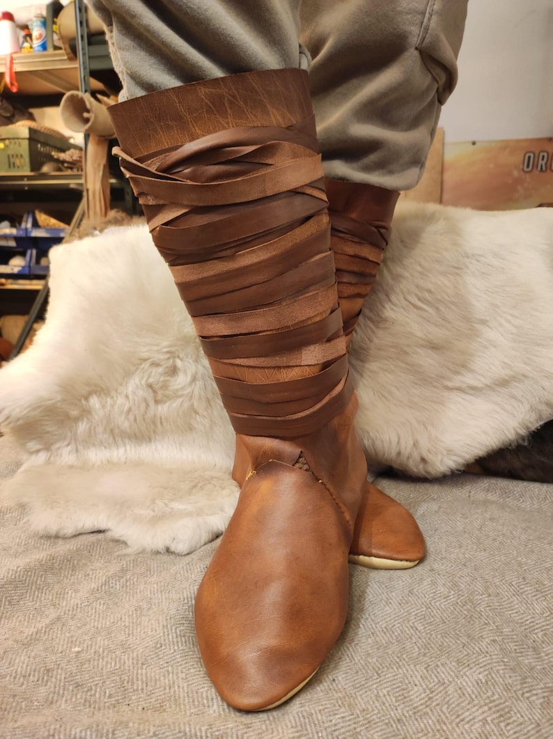 May include: Brown leather boots with a laced up design. The boots are tall and have a pointed toe.
