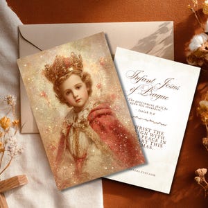 May include: A vintage-style greeting card featuring an illustration of the Infant Jesus of Prague wearing a crown and red robe. The card is accompanied by a second card with text, including "Infant Jesus of Prague" and a Bible verse. Dried flowers and a wooden cross are in the background.